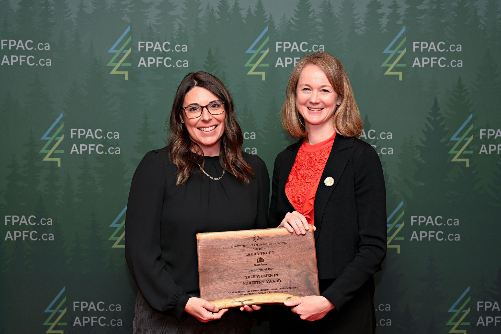 Two women stand against a green FPAC background for an award presentation.