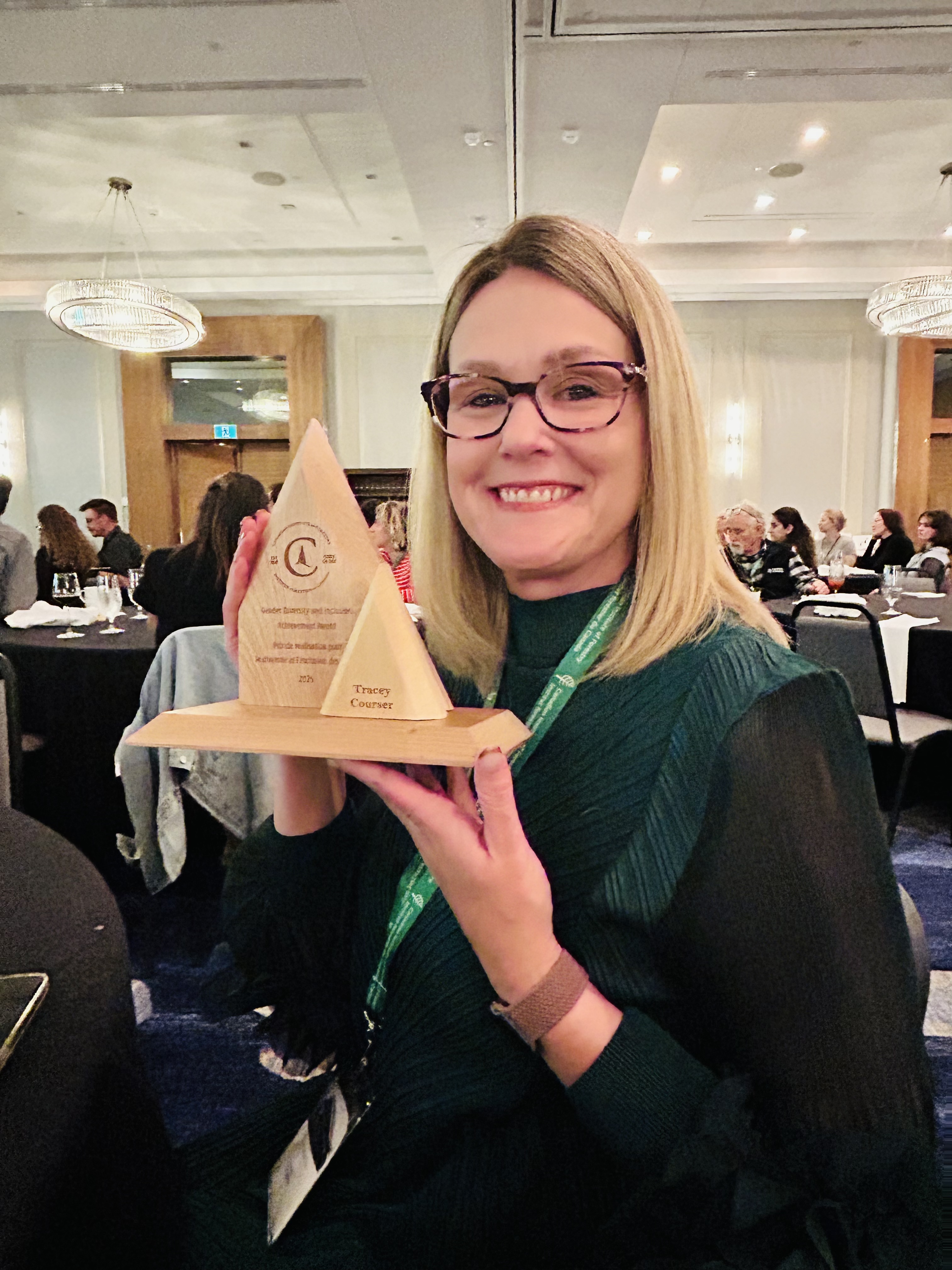 Woman in conference room holds up an award.