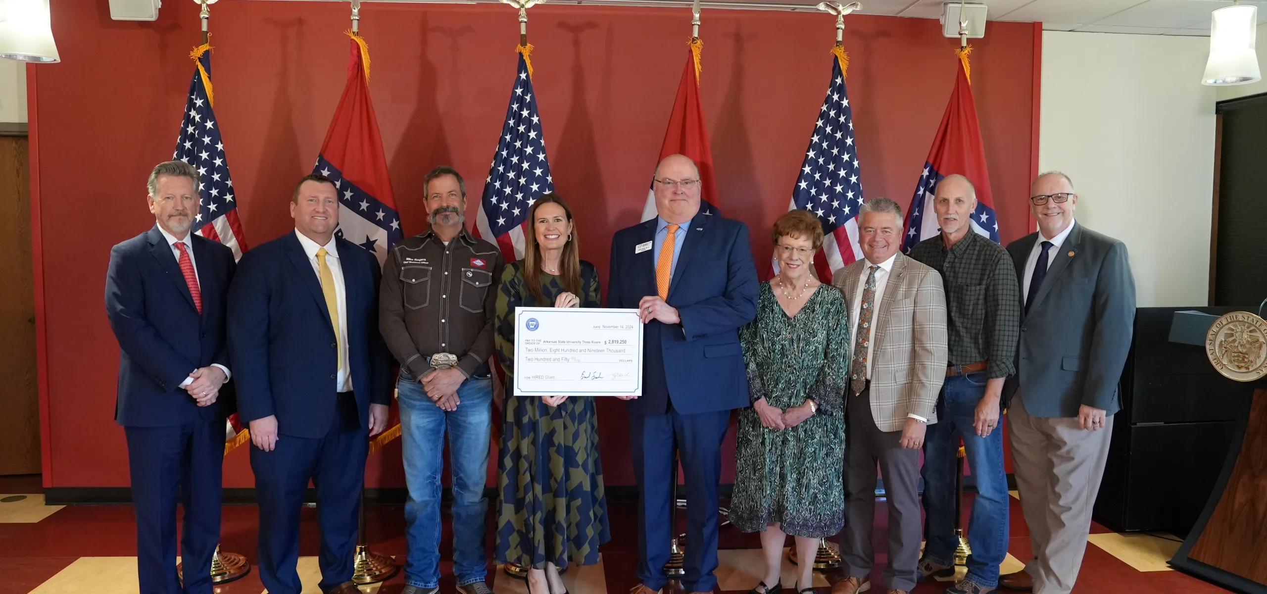Thomas “Tony” Byrd, Corporate Maintenance Trainer, West Fraser (second from right), and Arkansas Governor Sarah Huckabee Sanders and Dr. Steve Rook, ASUTR Chancellor (centre with cheque), stand with representatives from other organizations who contributed to the HIRED grant program.