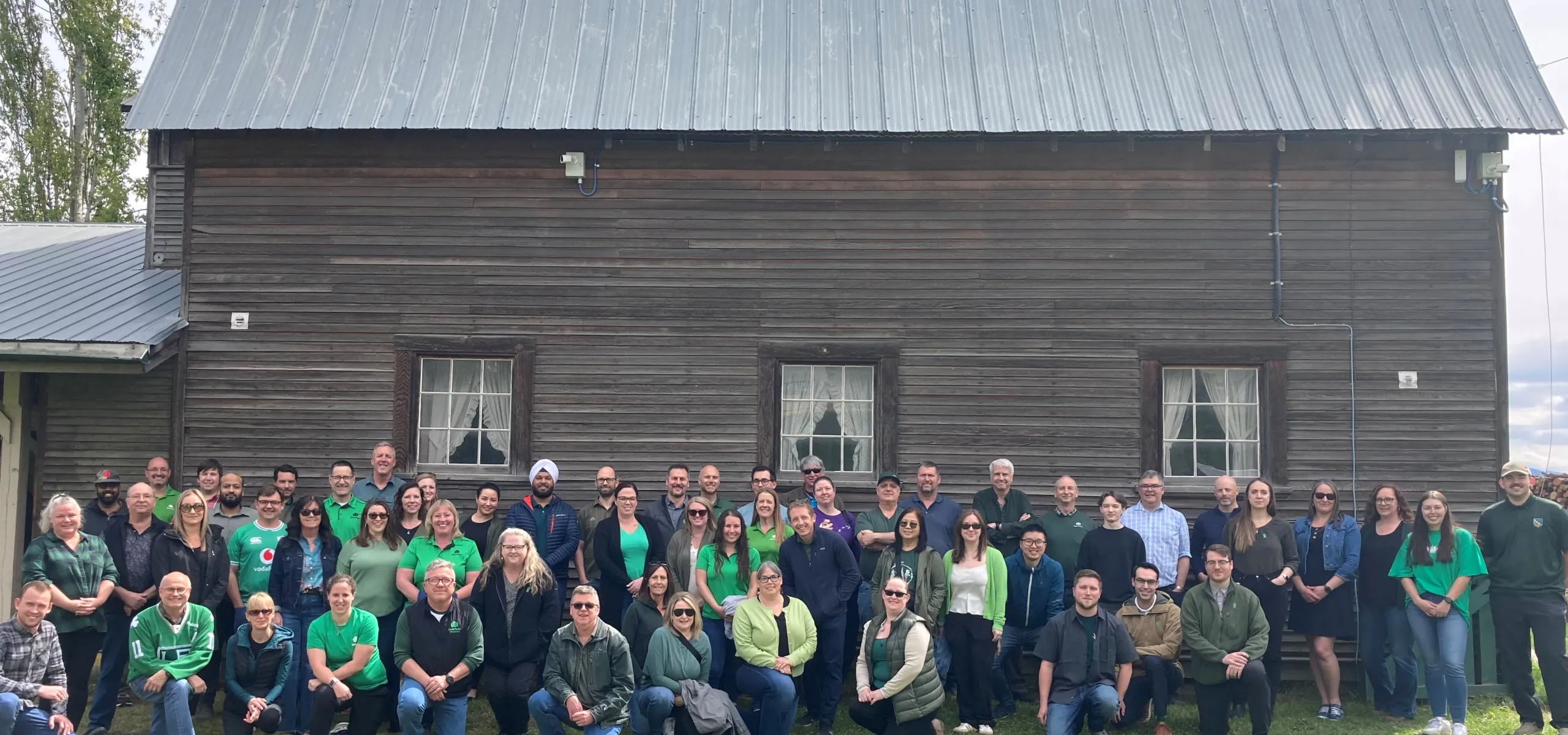 West Fraser team members pose in front of a wooden barn structure, on the site of the company's Quesnel location.
