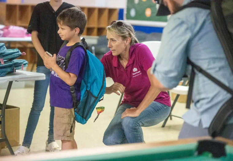West Fraser employee helps child with a donated backpack stuffed with school supplies.