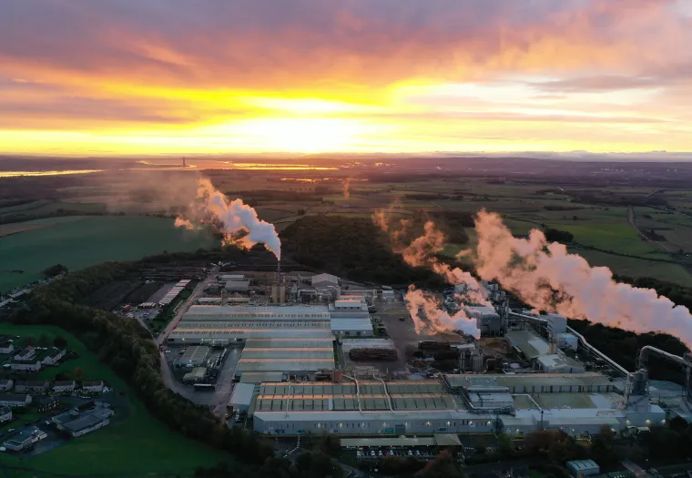 Aerial view of West Fraser's Cowie, Scotland mill at sunrise, surrounded by fields.