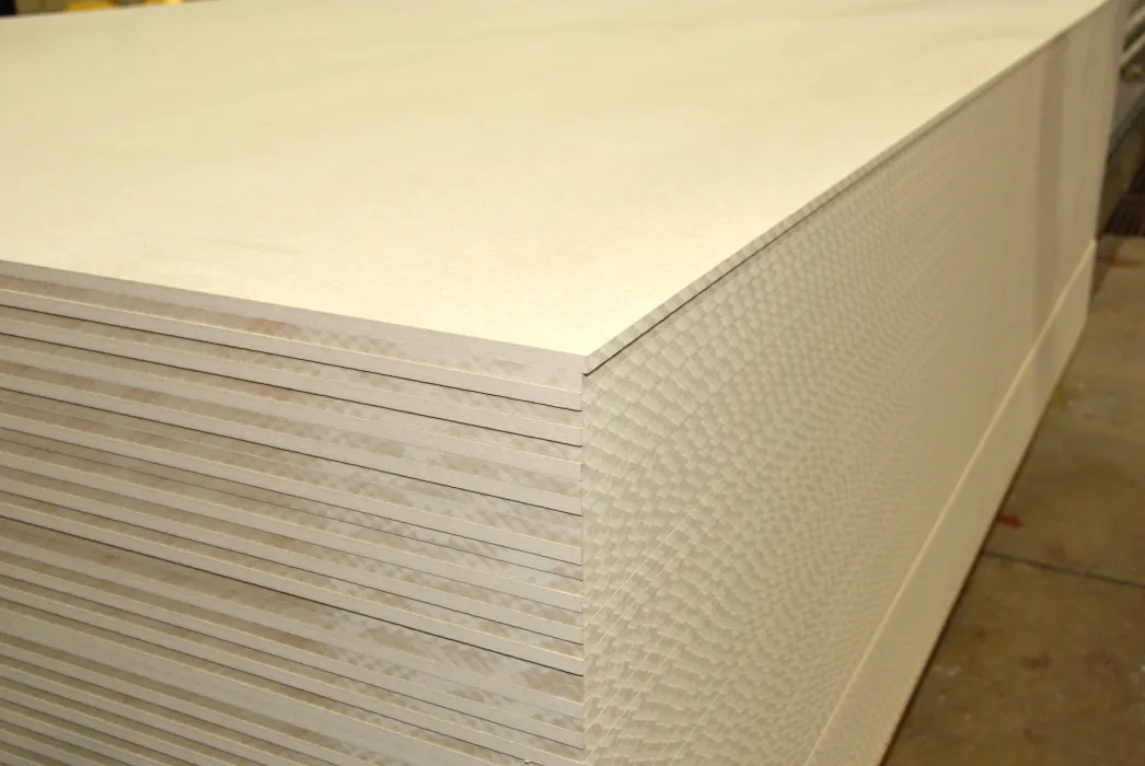 A stack of uniformly cut, light-colored plywood sheets placed on top of each other in a workshop setting.