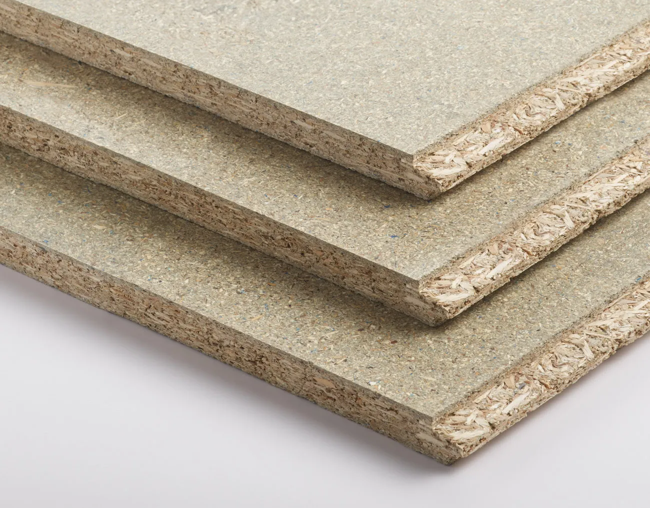 Close-up of three stacked particle boards with visible wood chips and layered texture on the edges.