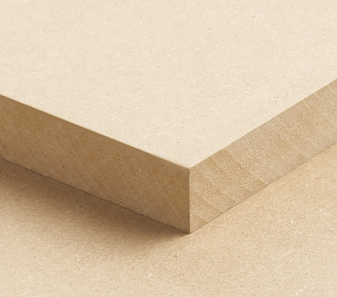 Close-up of a beige MDF board with a smooth surface and sharp edges, positioned diagonally against an identical board beneath it.
