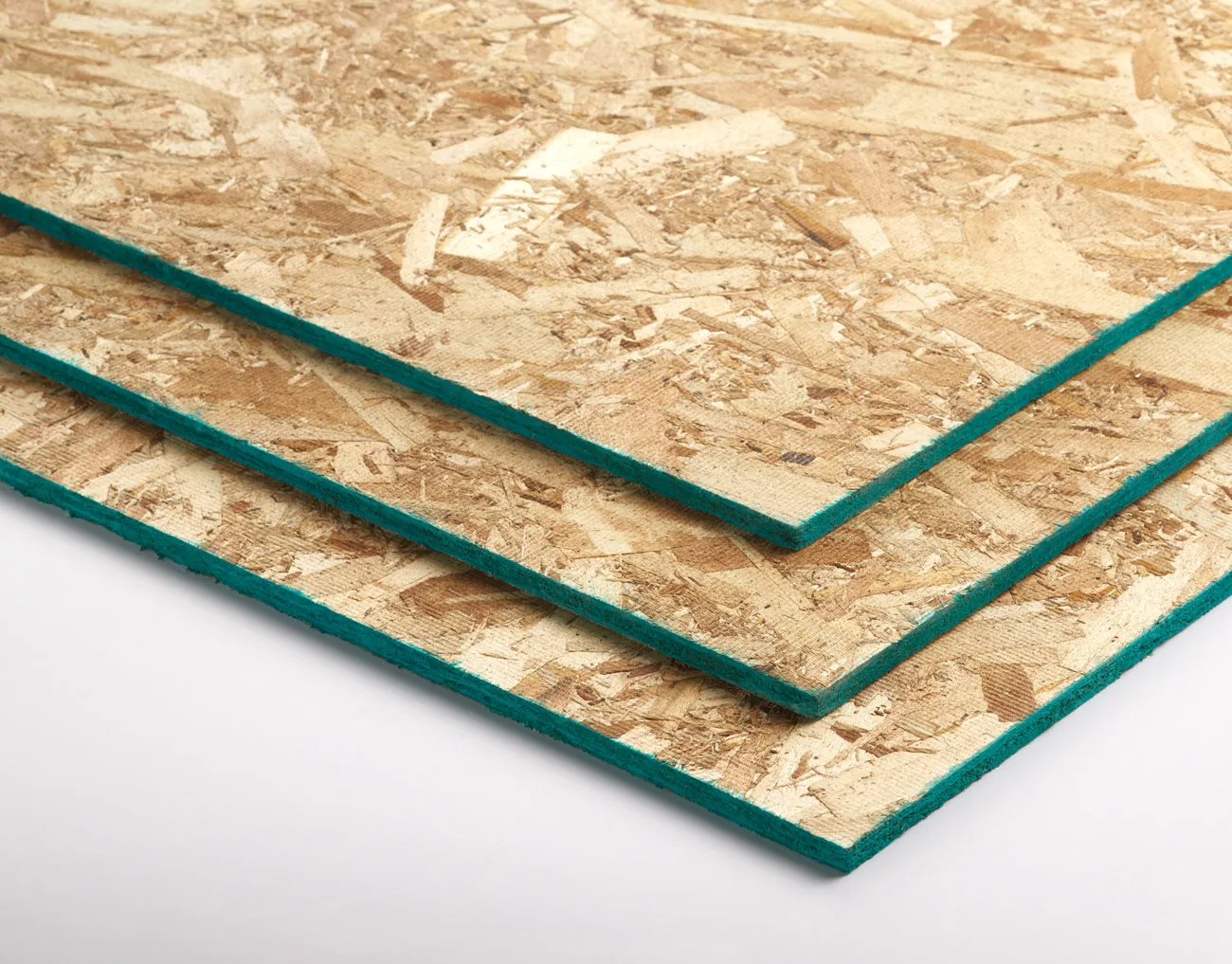 Three sheets of particle board with green edges stacked on a white surface.