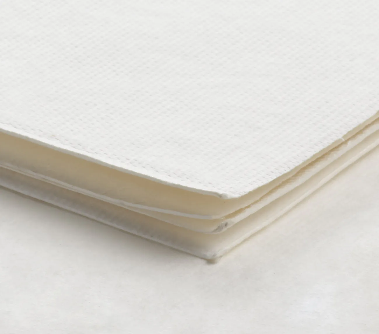 A stack of white paper napkins on a white surface.
