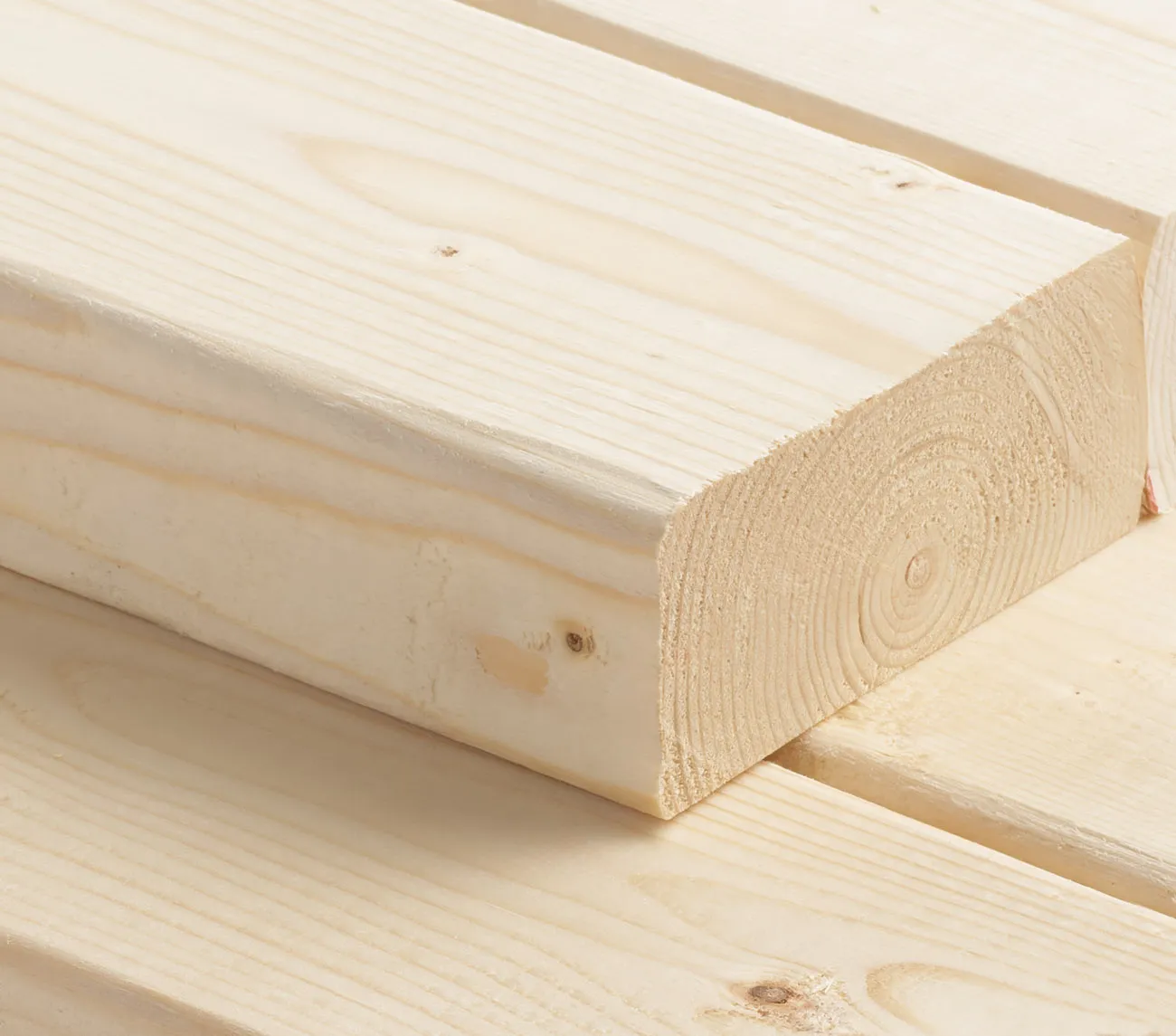 Close-up of stacked light-colored wooden planks with visible grain patterns.