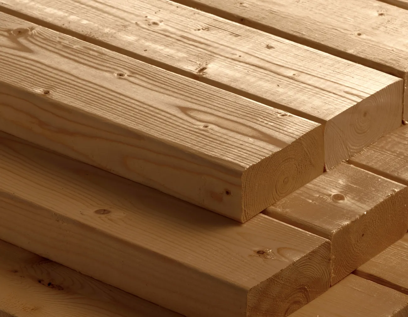 Stack of smooth, rectangular wooden planks with visible grain patterns, neatly arranged in a close-up view.