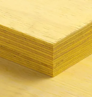 Close-up of a stack of yellow plywood sheets with visible layers and a smooth surface.
