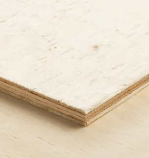 A close-up of the corner of a wood panel showing its layered structure, placed on a light wooden surface.