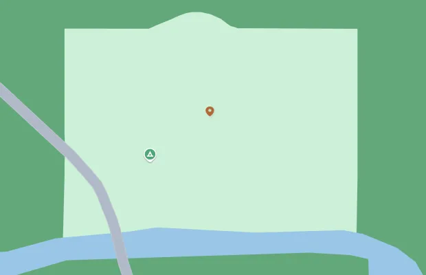 Map showing a camping location beside a river. The camping symbol is marked with a triangle and a dot marks another point of interest. A curved road is visible on the left side.