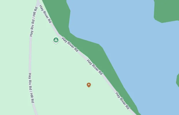 A map showing Hay River Road intersecting with an unlabeled water body on the right. The road is labeled in multiple places. There is a green area on the top-left and a marker and green triangle on the map.
