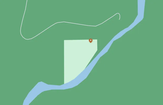 Map showing a light green rectangular area bordered by a river on the right and curved roads on the top and left. A red pin marker is located in the upper portion of the rectangle.