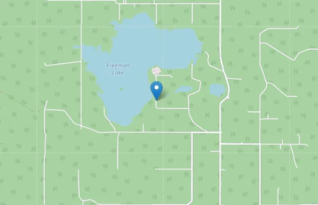 Map showing Freeman Lake surrounded by roads and forested areas, with a blue location marker placed on the southern edge of the lake.