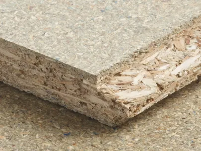 Close-up of a textured particle board showing layers of compressed wood chips and fibers on a flat surface.
