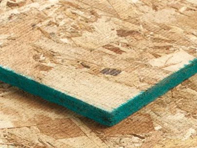 Close-up of a wooden chipboard panel with a green edge, resting on another identical panel.