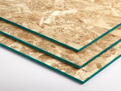 Three sheets of particle board with green edges stacked on a white surface.