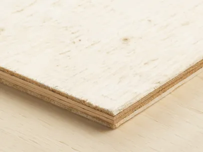 A close-up of the corner of a wood panel showing its layered structure, placed on a light wooden surface.
