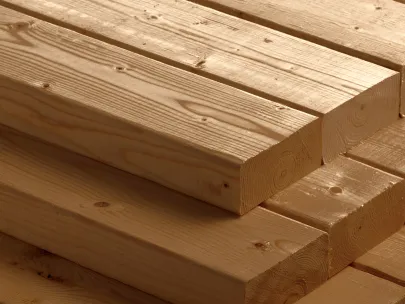 Stack of smooth, rectangular wooden planks with visible grain patterns, neatly arranged in a close-up view.
